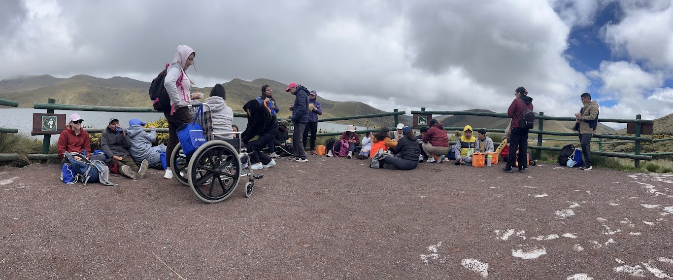 Montaña para Todos group resting by a páramo lake, with a participant in a wheelchair